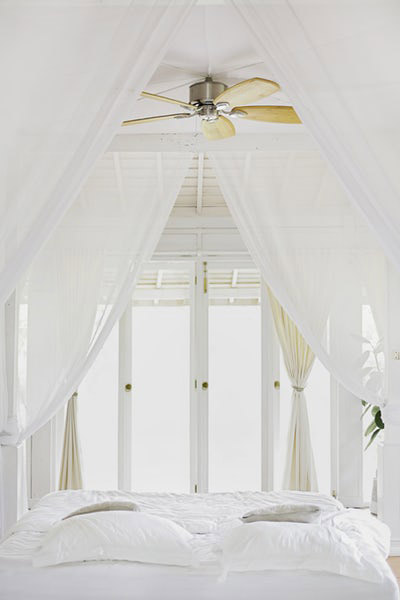 Bed in a white room with ceiling fan and patio doors