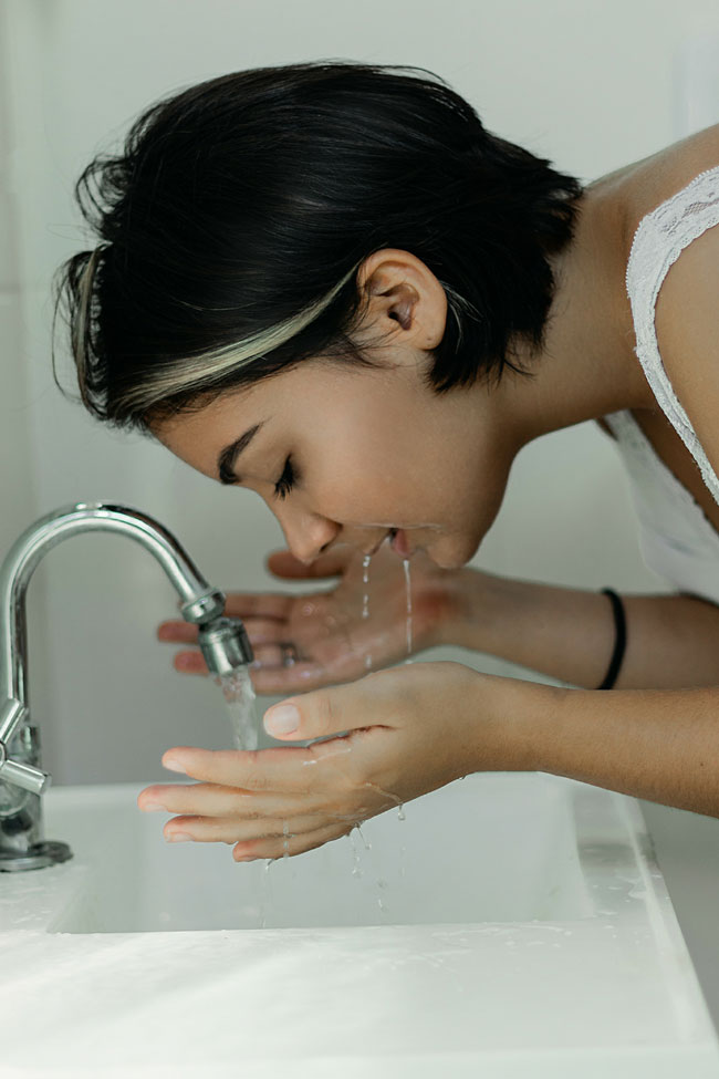 Woman washing face at sink