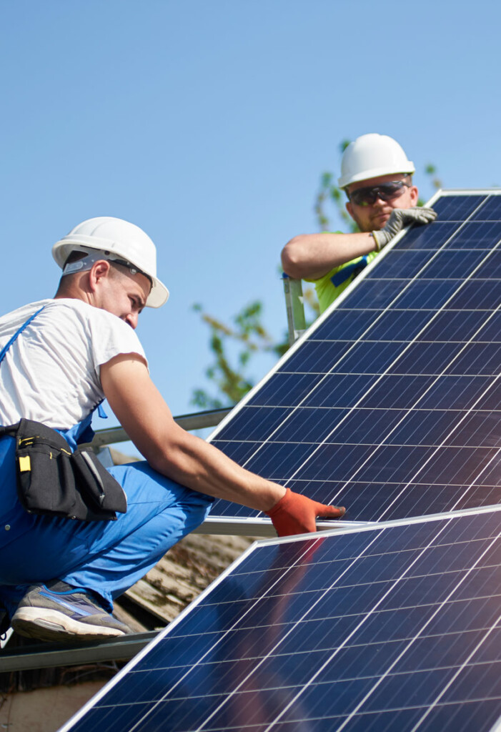 Workmen installing solar panels on roof