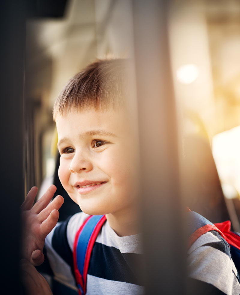 Little boy waving from bus window