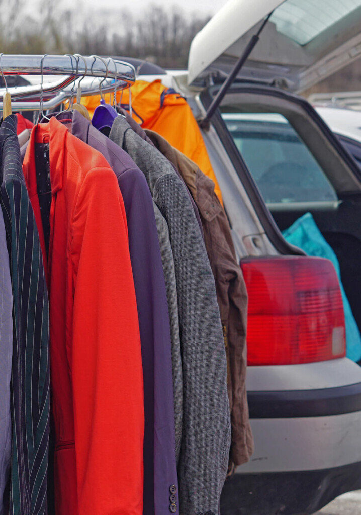 Old clothes on a hanging rail at a car boot sale.