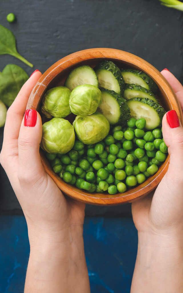 Hands holding bowl of green vegetables