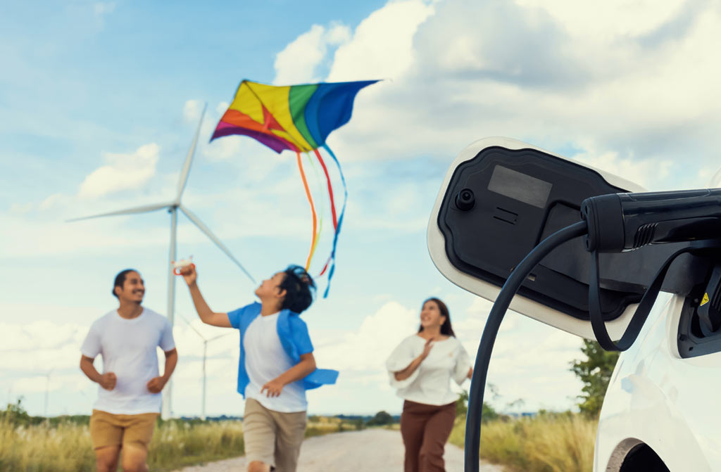 Family with electric vehicle and wind turbines in the background